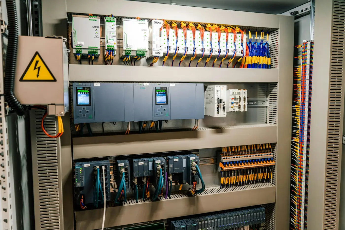 PLC controllers, power supplies, network switches and terminal blocks in a control cabinet