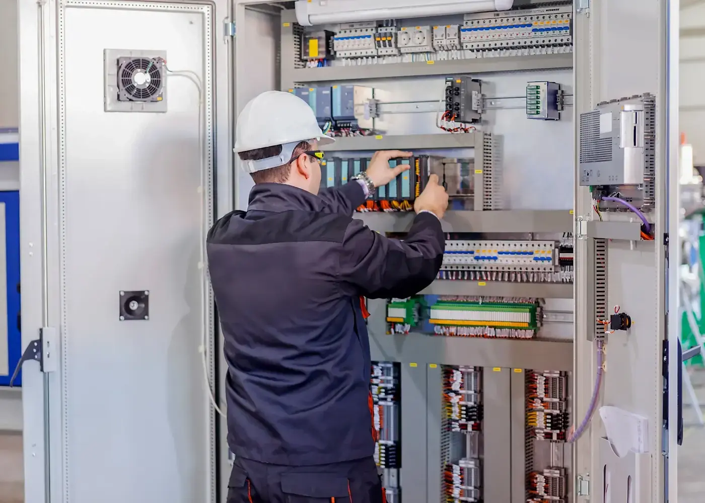 Technician working on components inside an industrial electrical control cabinet